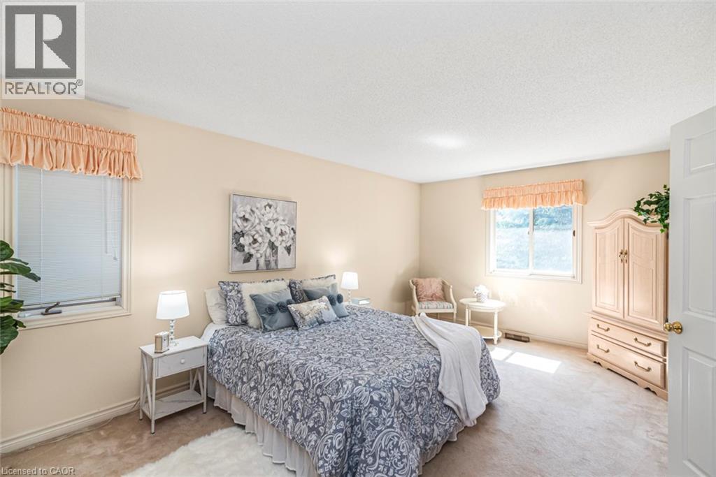Carpeted room featuring two windows with valances and blinds, neutral wall tones, a recessed light fixture, and a paneled white door - 85 Citation Crescent, Ancaster, ON