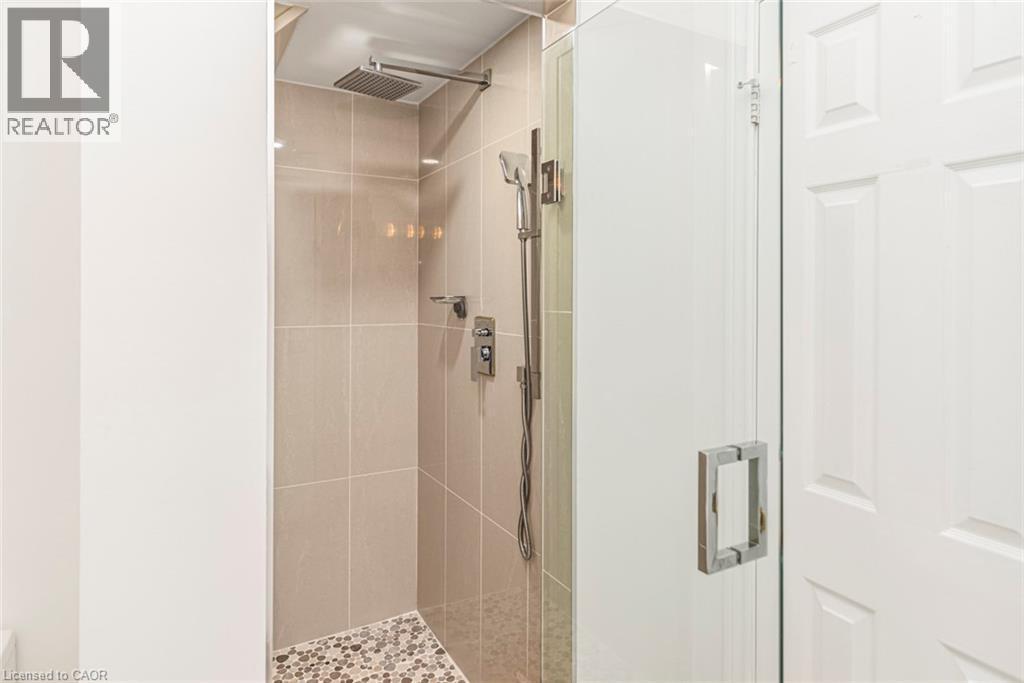 Glass-enclosed shower featuring large format wall tiles, a rain shower head, handheld shower fixture, and a mosaic tile floor - 85 Citation Crescent, Ancaster, ON