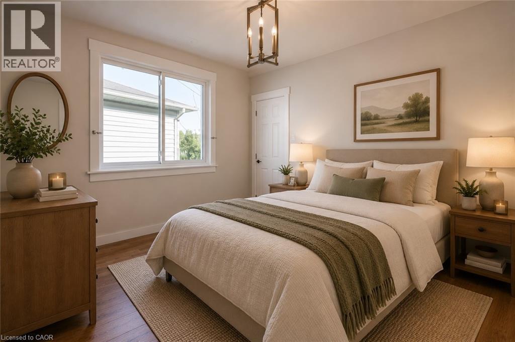 Bedroom featuring light-toned walls, wood-finish flooring, and a large sliding window with white trim - 204 Glow Avenue Unit# Upper, Hamilton, ON