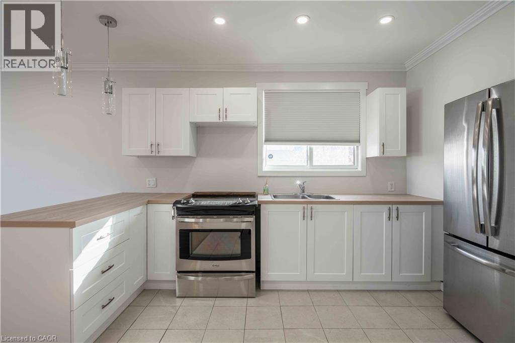 Kitchen featuring white shaker-style cabinetry, wood-finish countertops, stainless steel appliances, and tiled flooring - 204 Glow Avenue Unit# Upper, Hamilton, ON