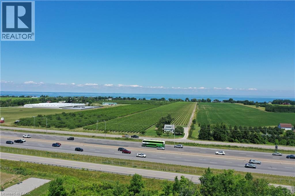 Expansive agricultural land featuring vineyards and fields, bordered by a highway and distant body of water - 3705 Service Road N, Beamsville, ON