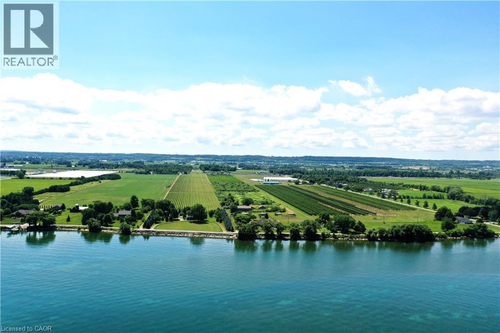 Expansive waterfront property featuring mature trees and a manicured lawn bordering the water - 3705 Service Road N, Beamsville, ON