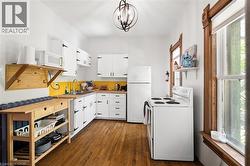 Kitchen featuring wood-finish flooring, white cabinetry with black hardware, and a bright yellow backsplash -