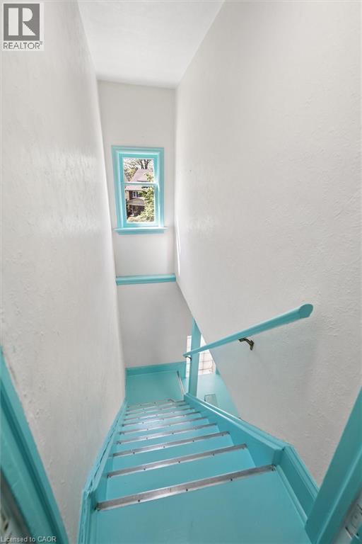 Staircase featuring teal painted risers, treads, and handrail, with white walls - 149 Young Street, Kitchener, ON - Indoor Photo Showing Other Room