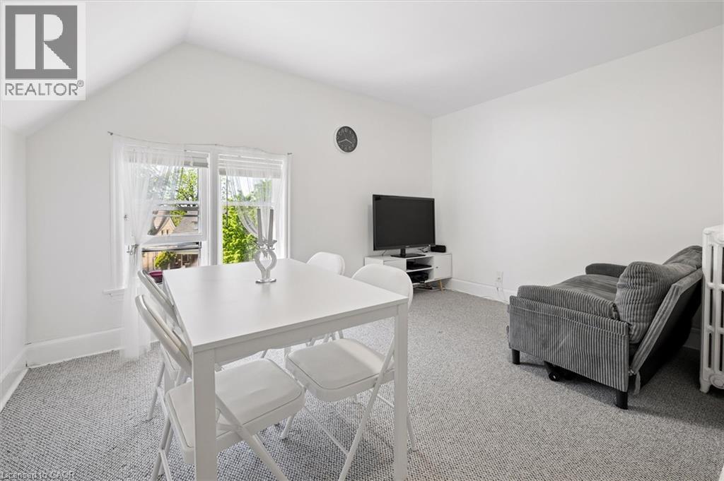 Bright interior space featuring a window with white sheers, light gray carpet, and white walls - 149 Young Street, Kitchener, ON - Indoor