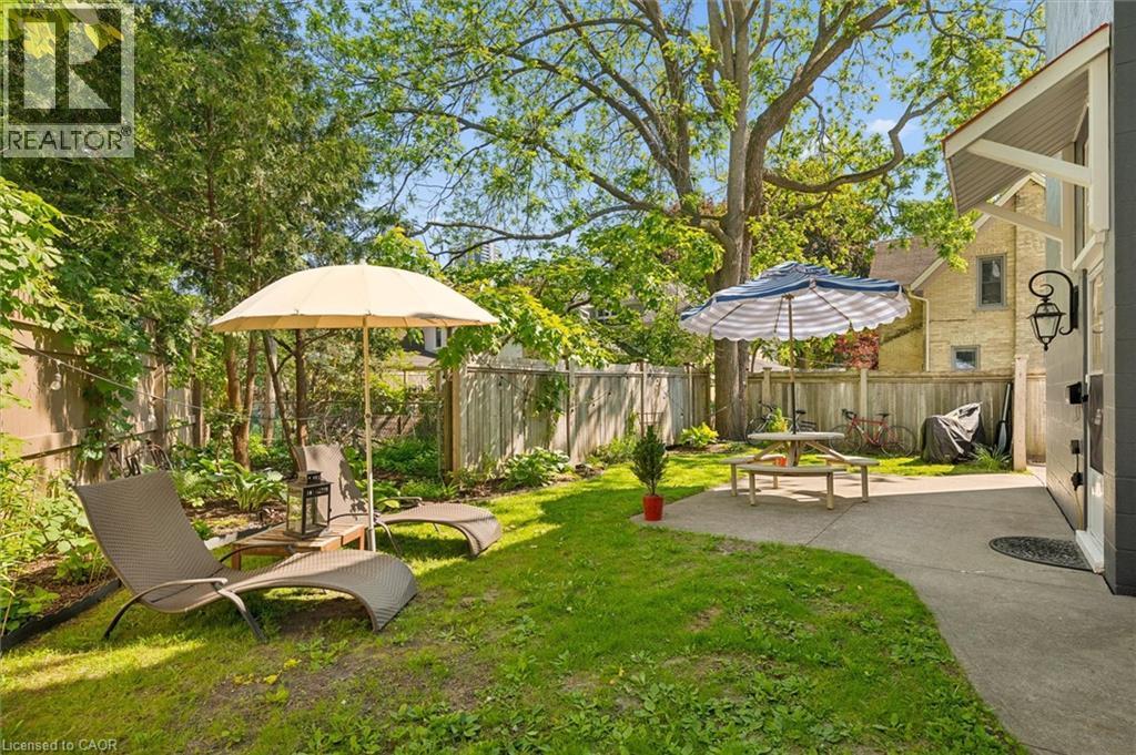 Expansive backyard featuring a manicured lawn, established trees, and a wooden privacy fence - 149 Young Street, Kitchener, ON - Outdoor With Backyard
