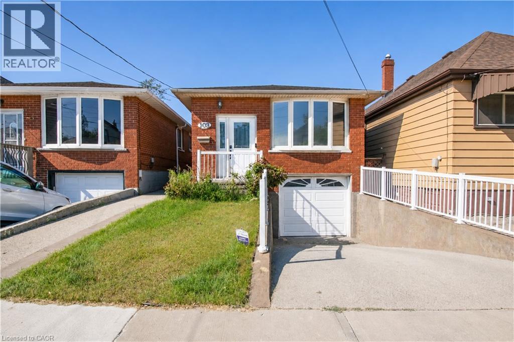 Brick exterior featuring a front entry, bay window, and an attached garage with a white door - 103 Mcanulty Boulevard Unit# Upper, Hamilton, ON