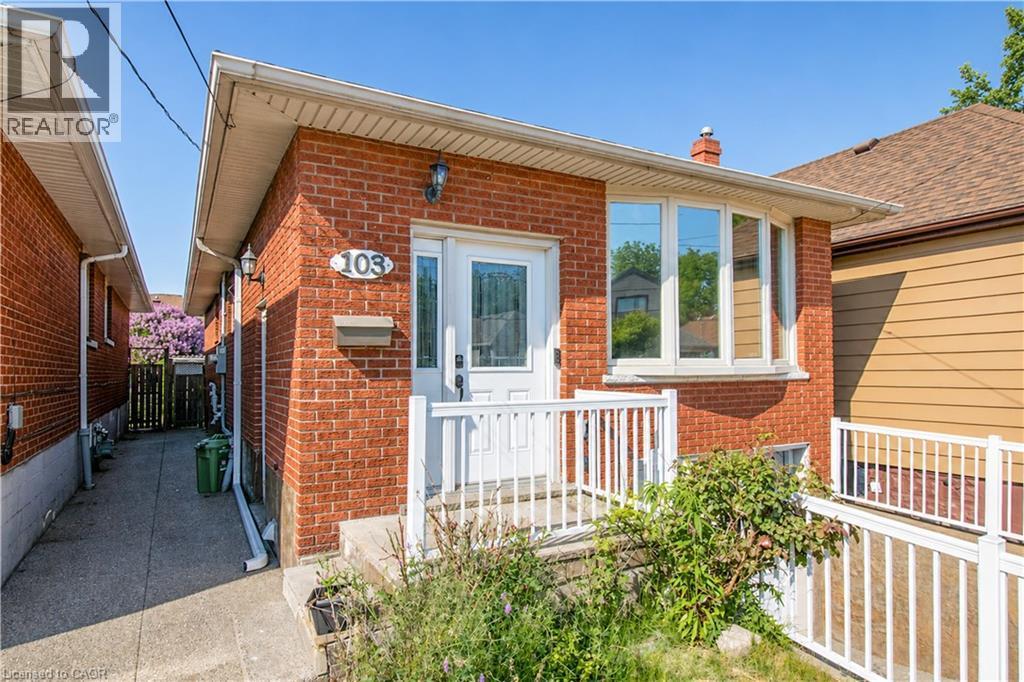 Brick exterior with a white entry door, an exterior wall light fixture, and a front bay window - 103 Mcanulty Boulevard Unit# Upper, Hamilton, ON