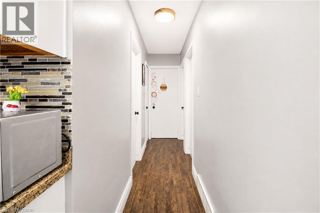 Hallway featuring wood-finish flooring, white baseboards, and a flush-mount ceiling light fixture - 103 Mcanulty Boulevard Unit# Upper, Hamilton, ON