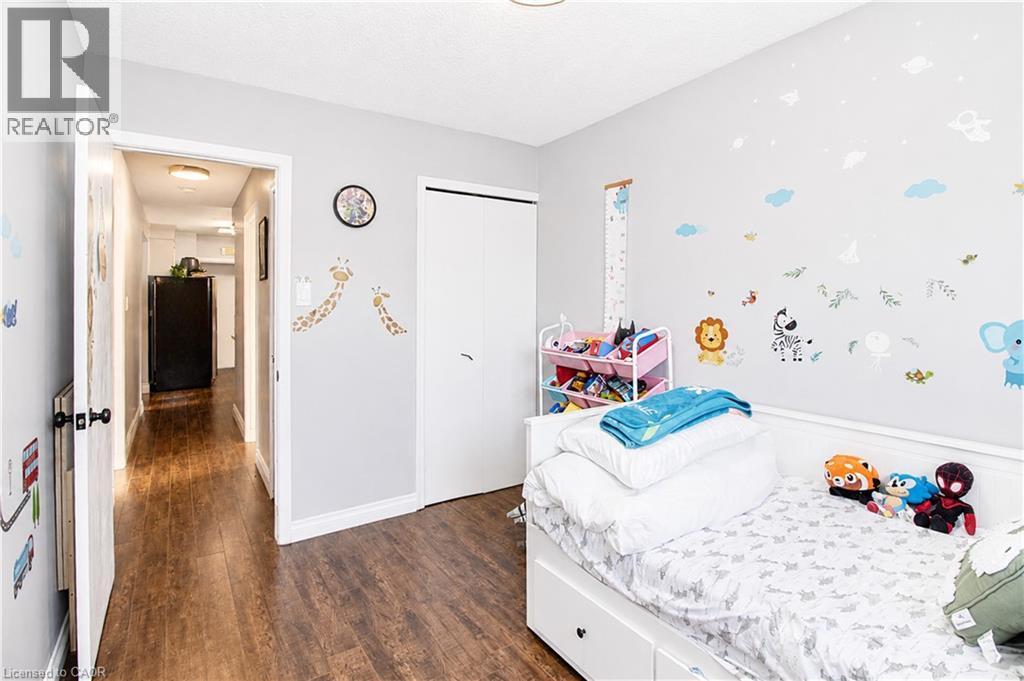 Bedroom with wood-finish flooring, light grey walls, and a white bi-fold closet door - 103 Mcanulty Boulevard Unit# Upper, Hamilton, ON