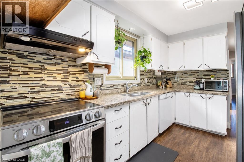 Kitchen featuring white cabinetry with dark hardware, a mosaic tile backsplash, and light-toned countertops - 103 Mcanulty Boulevard Unit# Upper, Hamilton, ON