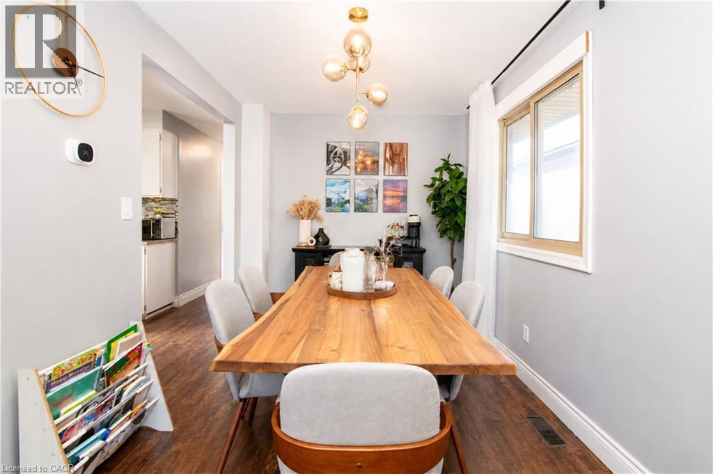 Dining area featuring a contemporary chandelier, wood-finish flooring, a large window, light gray wall paint, and white baseboards - 103 Mcanulty Boulevard Unit# Upper, Hamilton, ON