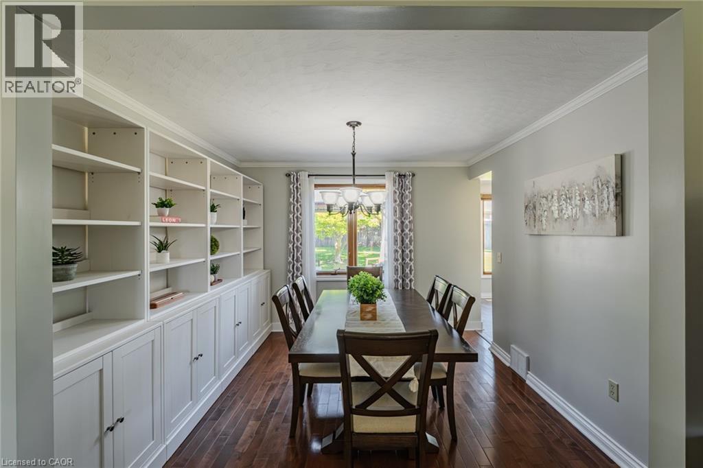 Dining area featuring extensive built-in shelving, rich wood-finish flooring, a window offering exterior views, and crown molding - 141 Lynndale Road, Simcoe, ON