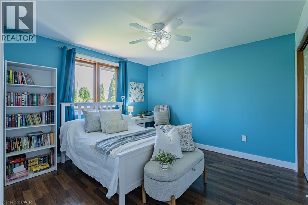 Bedroom featuring wood-finish flooring, a ceiling fan with integrated lighting, and a large window with white trim - 141 Lynndale Road, Simcoe, ON