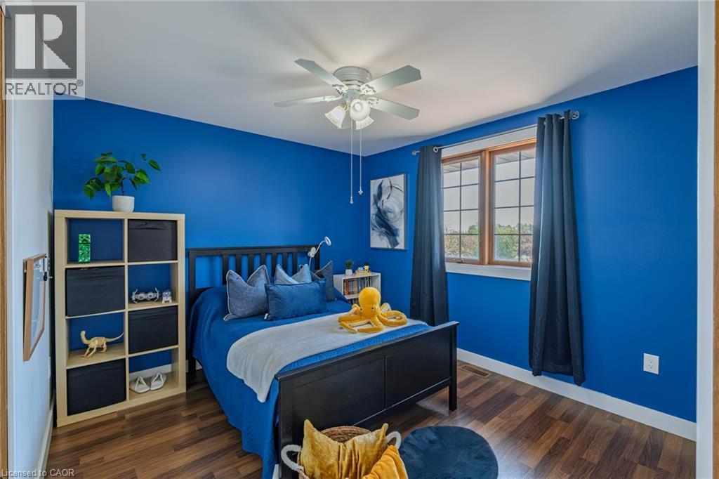 Bedroom featuring wood-finish flooring, a ceiling fan, and a window with wood trim - 141 Lynndale Road, Simcoe, ON