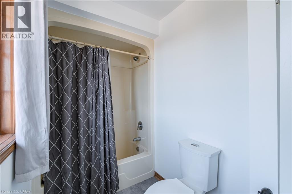 Bathroom featuring a white tub/shower combination, white toilet, and light gray flooring - 141 Lynndale Road, Simcoe, ON