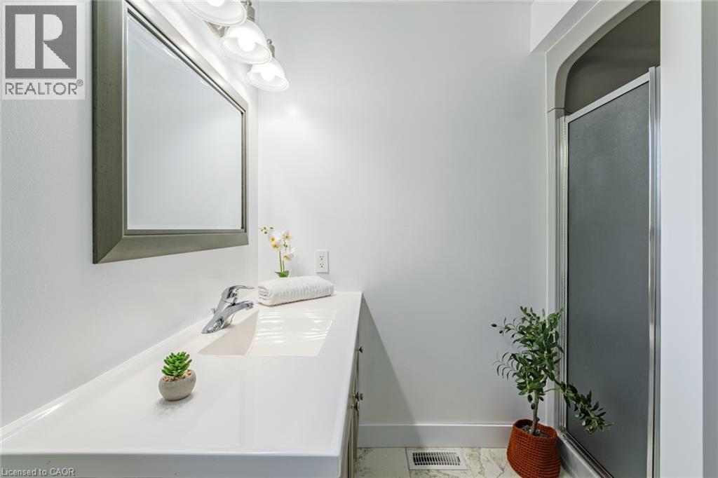 Bathroom featuring a single vanity with an integrated sink, polished chrome faucet, and a large framed mirror - 141 Lynndale Road, Simcoe, ON