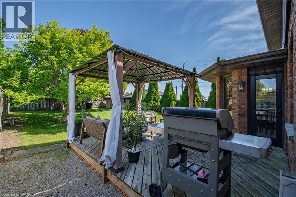Expansive wood deck with a built-in gazebo, featuring a canopy and privacy drapes - 141 Lynndale Road, Simcoe, ON