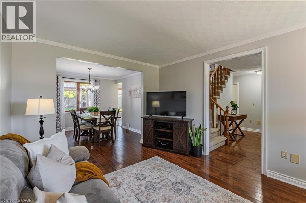 Spacious living area featuring wood-finish flooring, a dining area beyond, and a visible staircase - 141 Lynndale Road, Simcoe, ON
