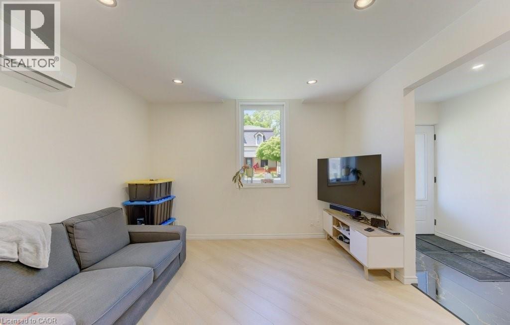 Bright interior space featuring light wood-finish flooring, recessed lighting, and a white wall-mounted mini-split HVAC unit - 11 Davidson Street, Cambridge, ON