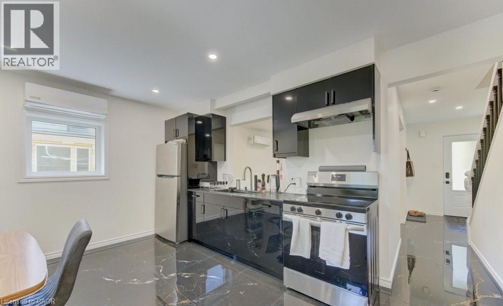 Modern kitchen featuring sleek black cabinetry, stainless steel appliances, and a dark marble-patterned flooring - 11 Davidson Street, Cambridge, ON