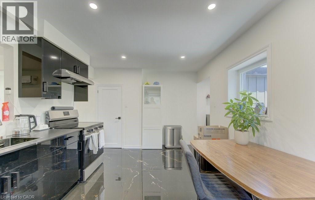 Contemporary kitchen featuring high-gloss black cabinetry, dark stone-finish countertops, stainless steel appliances, and recessed lighting - 11 Davidson Street, Cambridge, ON