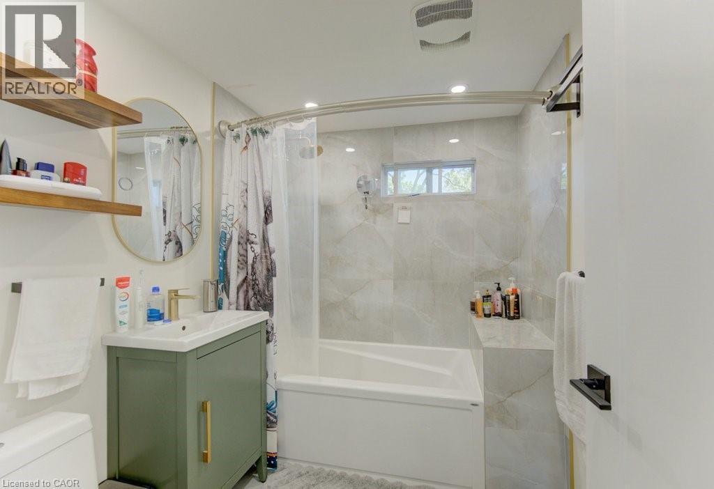 Contemporary bathroom featuring a white soaking tub with integrated shelving, light-toned patterned tile surround, and a compact window - 11 Davidson Street, Cambridge, ON