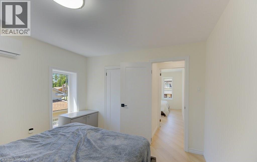 Bright room featuring light wood-finish flooring, a contemporary ceiling light fixture, a window with exterior views, and an internal entry door - 11 Davidson Street, Cambridge, ON