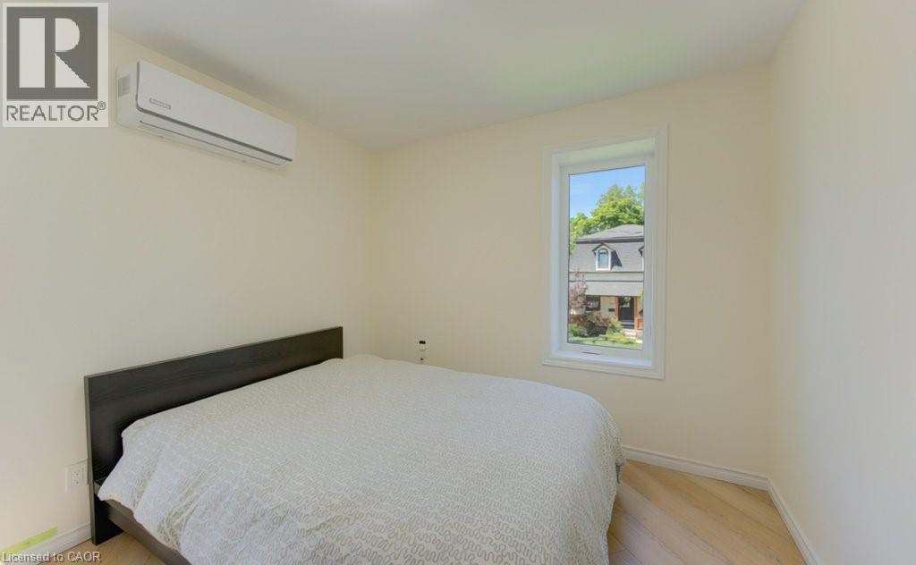 Light wood-finish flooring, a wall-mounted mini-split HVAC unit, and a single window with white trim - 11 Davidson Street, Cambridge, ON