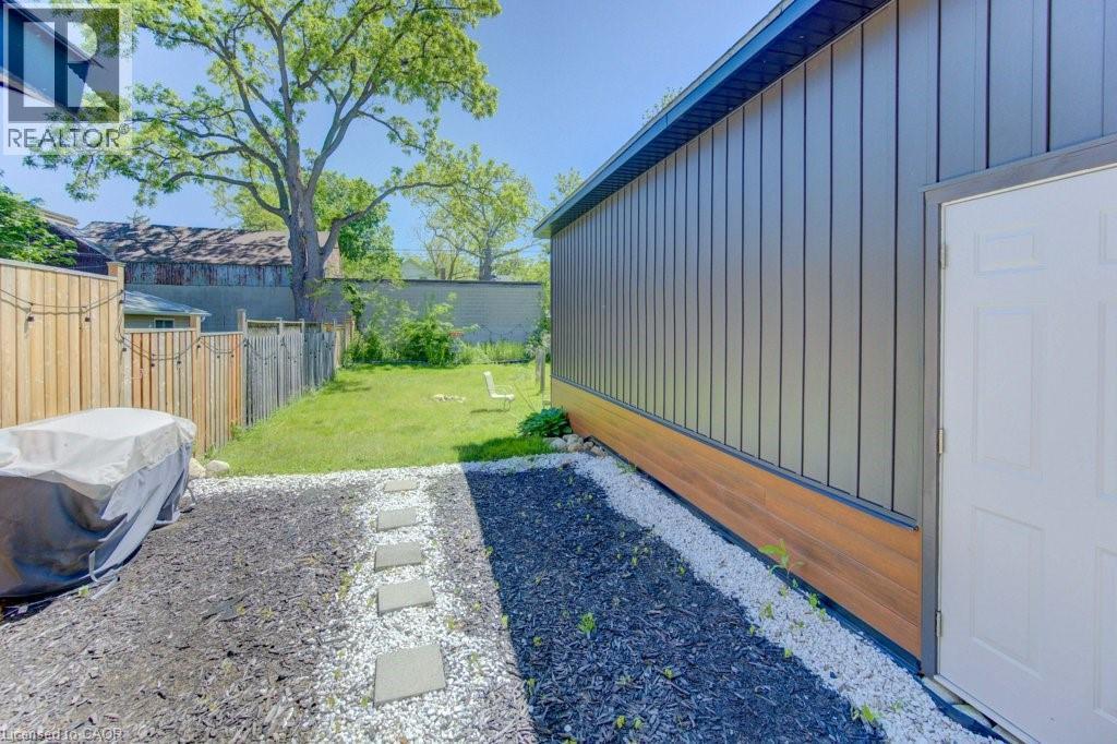 Landscaped backyard featuring a grass lawn, wood fencing, and a stone paver pathway - 11 Davidson Street, Cambridge, ON