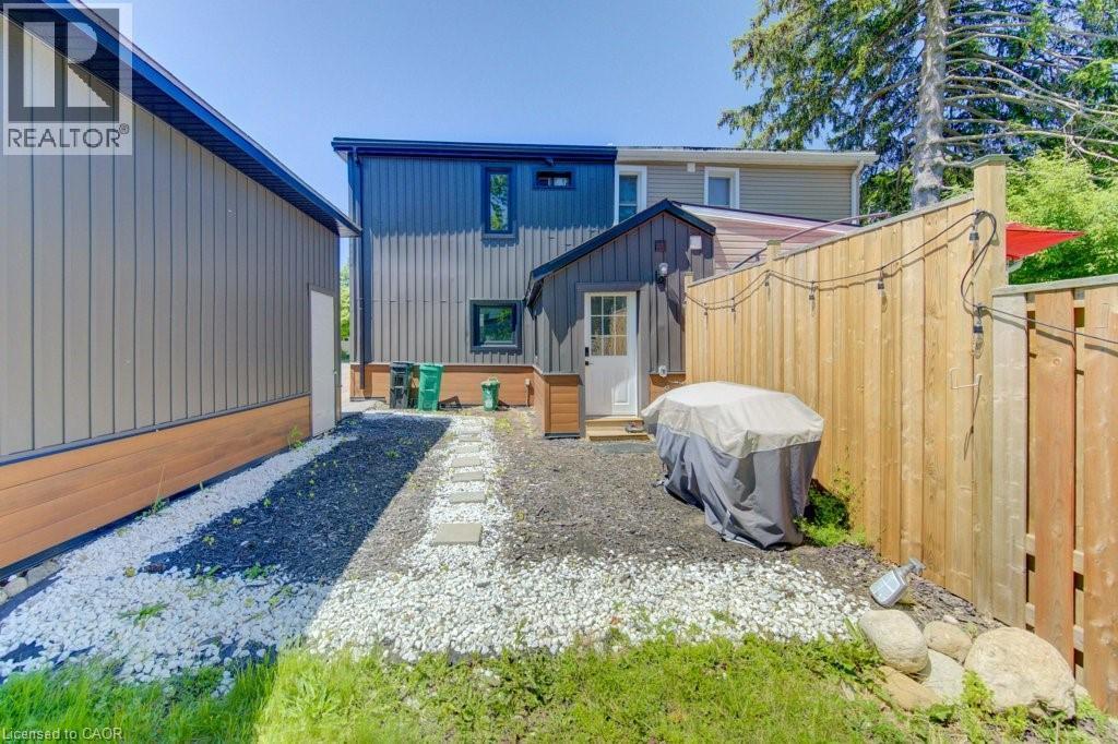 Rear exterior featuring vertical siding, a white entry door, and a stone pathway - 11 Davidson Street, Cambridge, ON