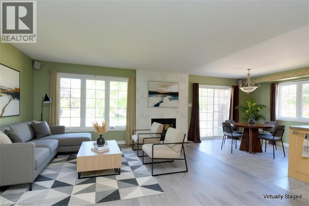 Open concept living and dining area featuring a fireplace with a light-toned surround, expansive windows, wood-finish flooring, and recessed lighting - 2 Harbour Drive Unit# 17, Stoney Creek, ON