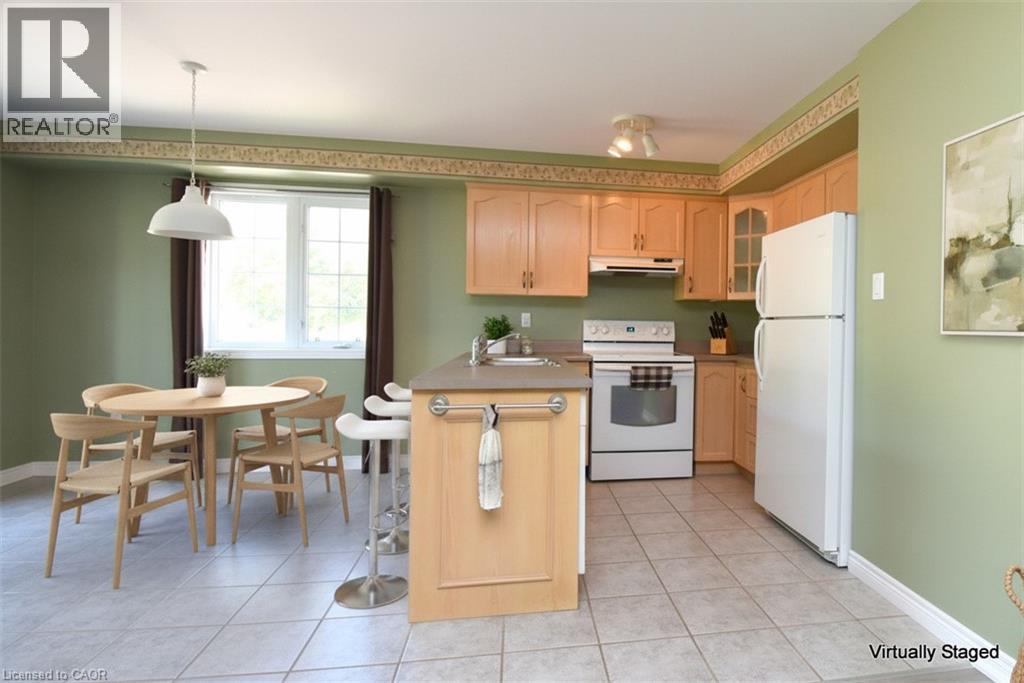 Kitchen with light wood cabinetry, white appliances, and a built-in breakfast bar - 2 Harbour Drive Unit# 17, Stoney Creek, ON