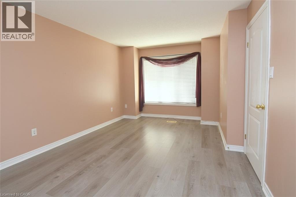 Spacious room featuring light wood-finish flooring, neutral wall tones, and white baseboards - 2 Harbour Drive Unit# 17, Stoney Creek, ON