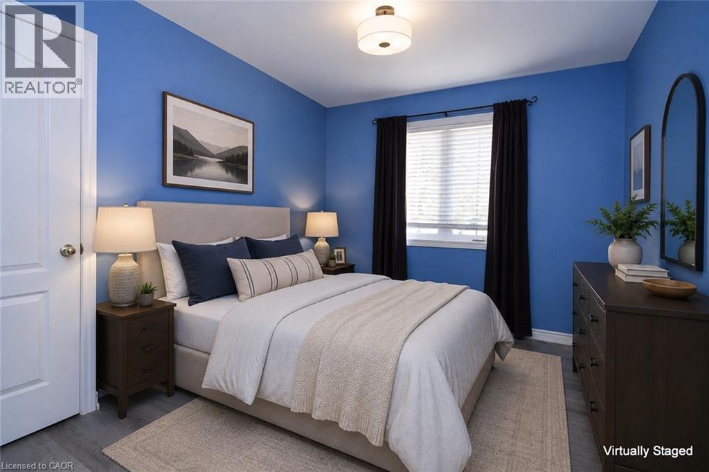 Bedroom featuring wood-finish flooring, a white interior door, a window with blinds, and a built-in flush mount ceiling light - 2 Harbour Drive Unit# 17, Stoney Creek, ON