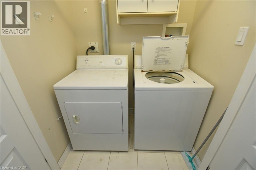 Dedicated laundry area featuring a white top-load washing machine and a white front-load dryer - 2 Harbour Drive Unit# 17, Stoney Creek, ON