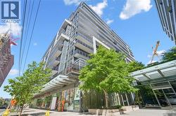 Modern residential high-rise with a sleek facade, featuring multiple private balconies with glass railings -