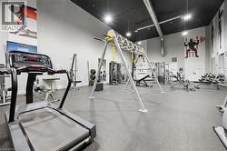 Spacious fitness center featuring high ceilings, exposed ductwork, rubber flooring, and a variety of exercise equipment including cardio machines and weight stations -