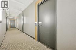 Carpeted corridor with light-toned walls and recessed panel ceiling details -