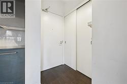 Entryway featuring a solid door with a door closer, dark wood-finish flooring, and white walls -