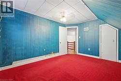 Unfurnished bedroom featuring wood walls, carpet, and ceiling fan -