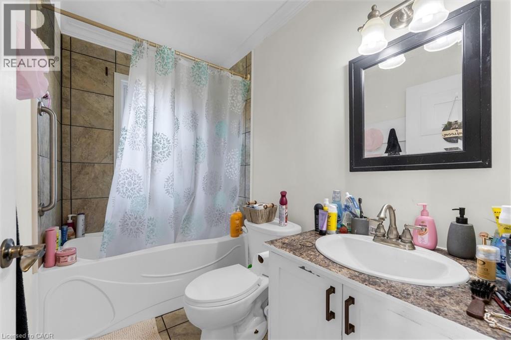 Bathroom featuring a vanity with an integrated sink, a framed mirror, and a three-light fixture - 406 East 43Rd Street, Hamilton, ON