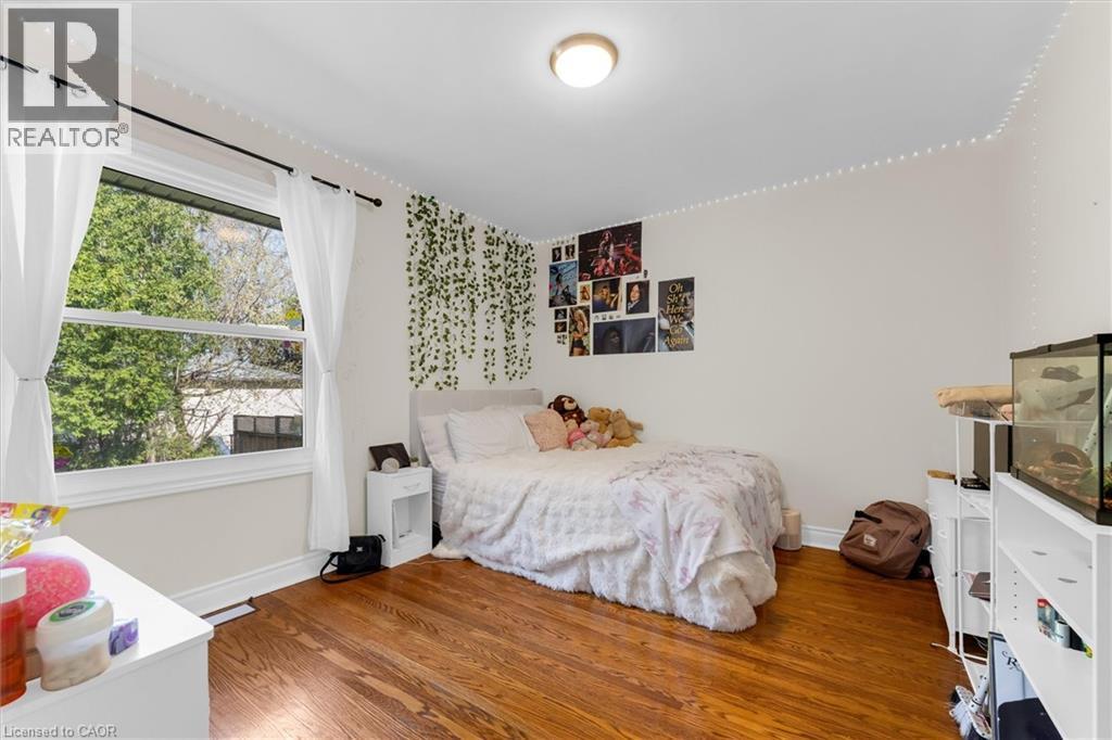 Bright interior space featuring a large window, wood-finish flooring, white walls, and a ceiling-mounted light fixture - 406 East 43Rd Street, Hamilton, ON