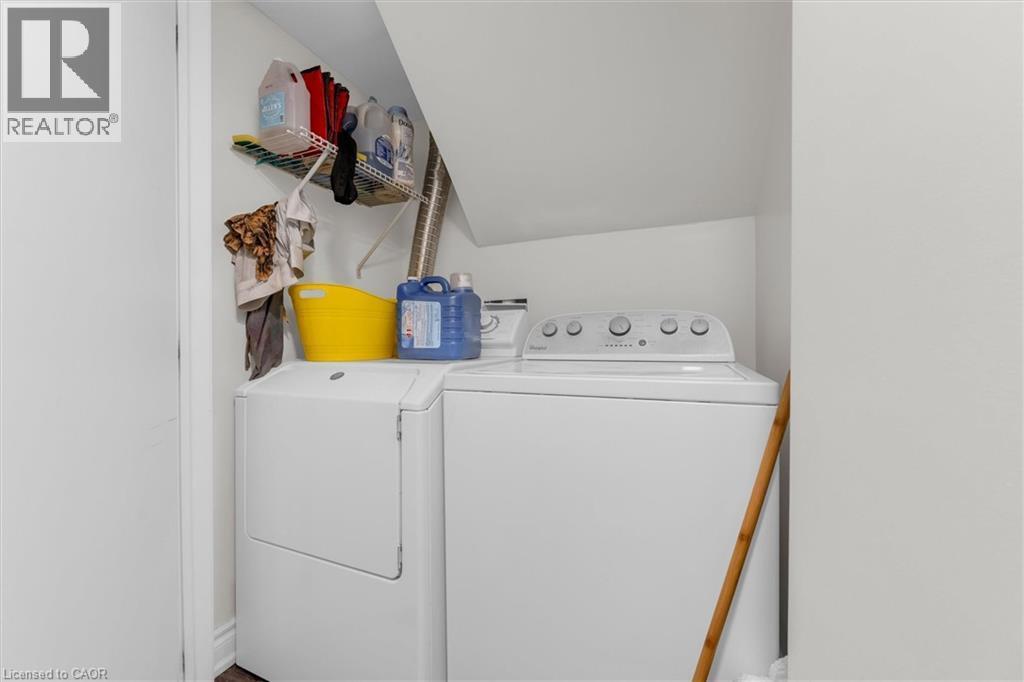 Dedicated laundry area featuring white appliances, upper wire shelving, and a sloped ceiling - 406 East 43Rd Street, Hamilton, ON