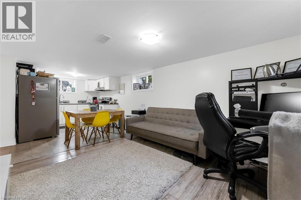 Open-concept living area featuring wood-finish flooring, a full kitchen with white cabinetry and a built-in range hood, and recessed lighting - 406 East 43Rd Street, Hamilton, ON