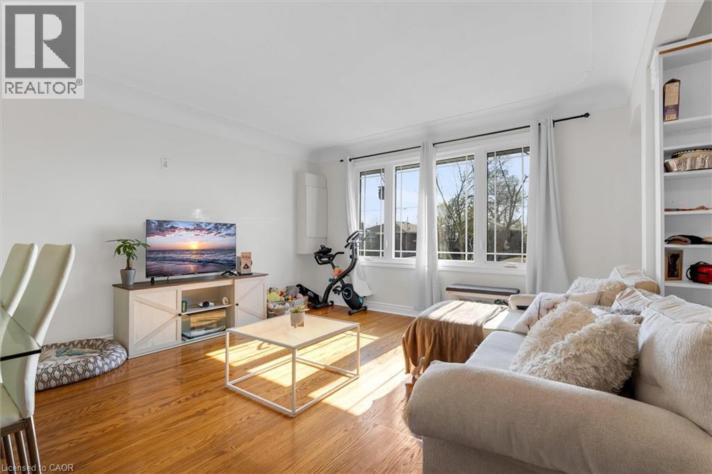 Living area featuring wood-finish flooring, a three-panel window with white trim, crown molding, and built-in shelving - 406 East 43Rd Street, Hamilton, ON