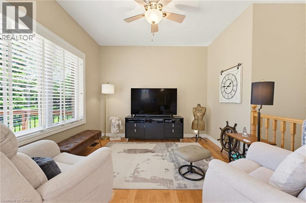 Living area featuring high ceilings, wood-finish flooring, and a large window with white horizontal blinds - 5 Coastal Court, Port Dover, ON
