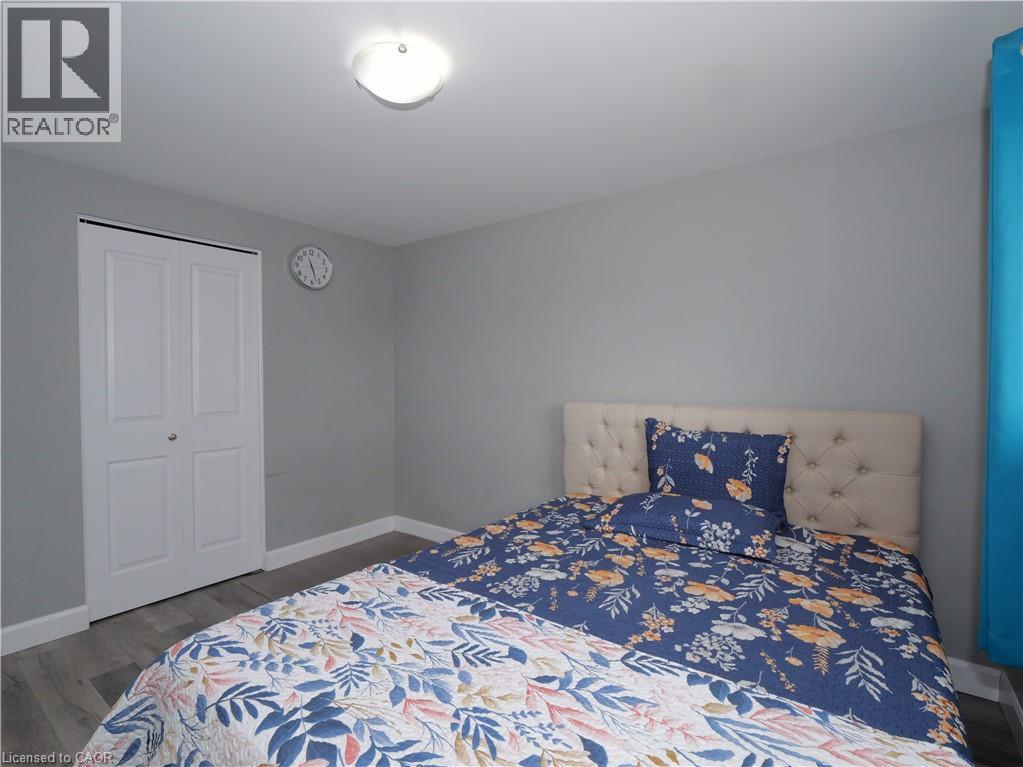 Interior room featuring light gray walls, wood-finish flooring, a flush-mount ceiling light, and white bi-fold closet doors - 771 Monsarrat Avenue, London, ON