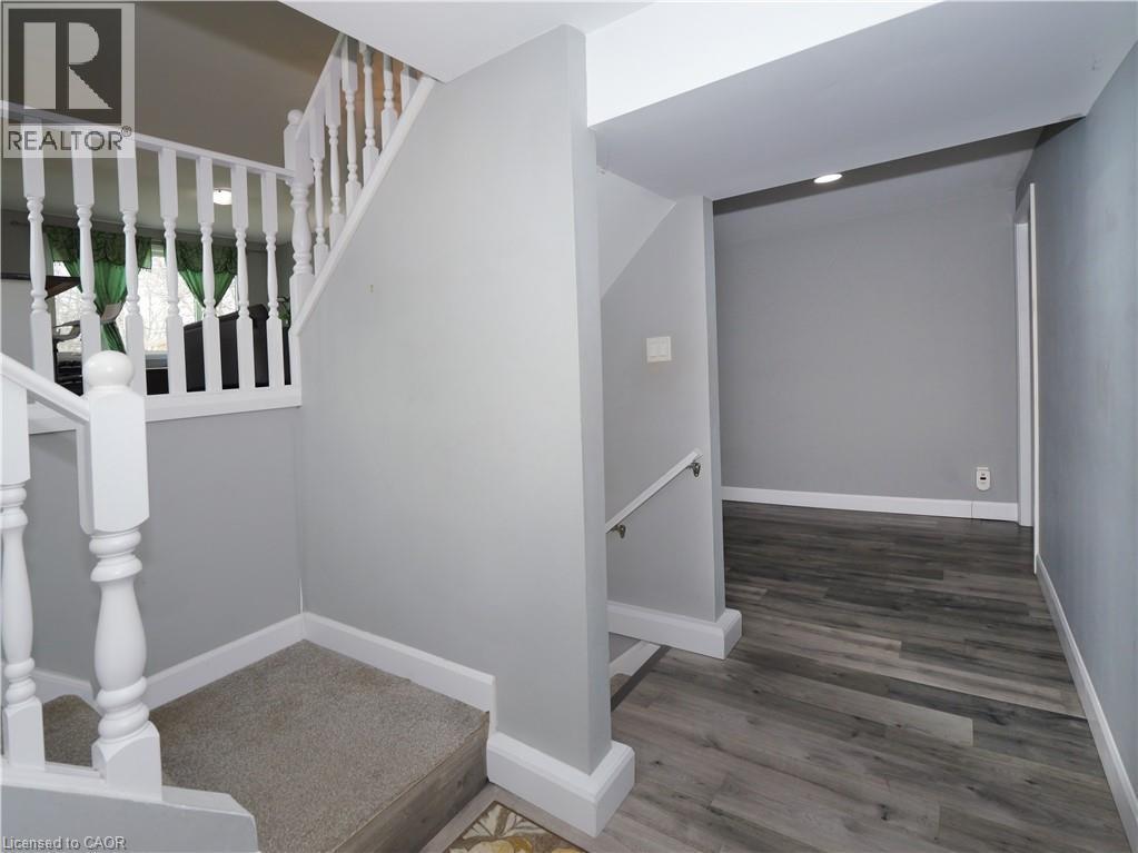 Interior hallway featuring light grey walls, white trim, and wood-finish flooring - 771 Monsarrat Avenue, London, ON