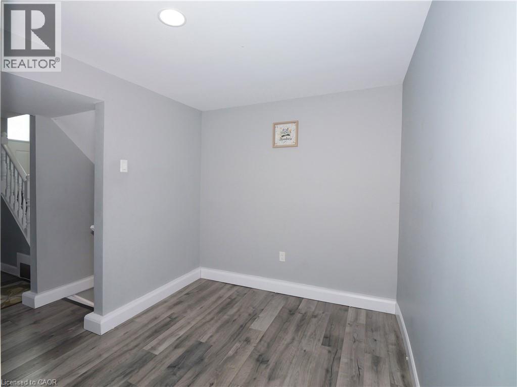 Spacious room featuring wood-finish flooring, light gray wall paint, white baseboards, and recessed ceiling lighting - 771 Monsarrat Avenue, London, ON
